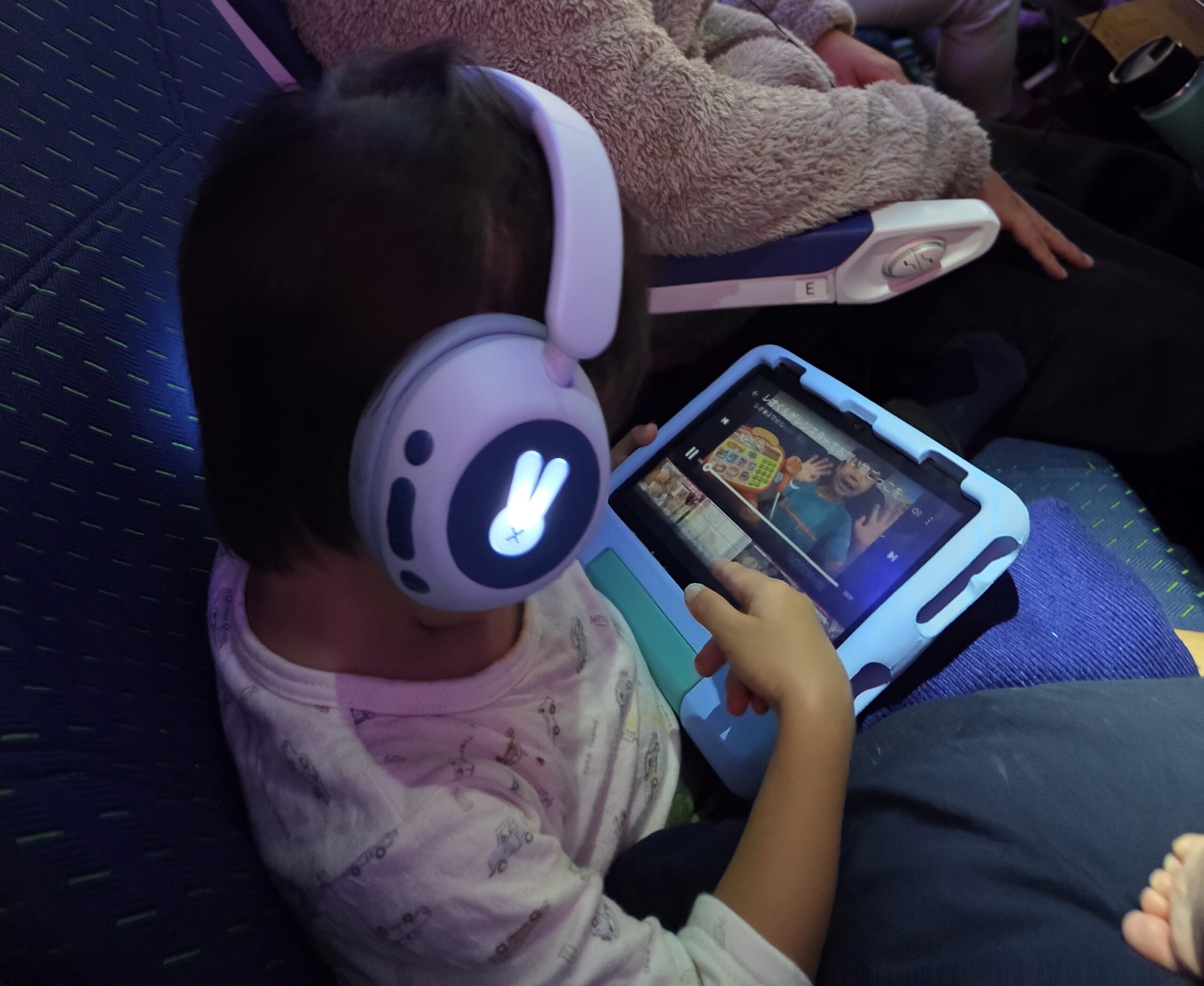 ANA機内で子ども用ヘッドホンを着けてタブレットを見る2歳児