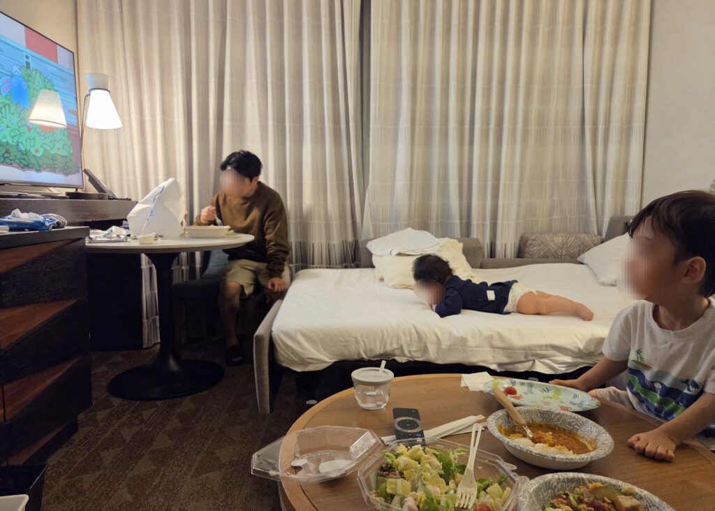 エンバシースイーツのソファベッドで寛ぐ次男と、ごはんを食べるパパと長男